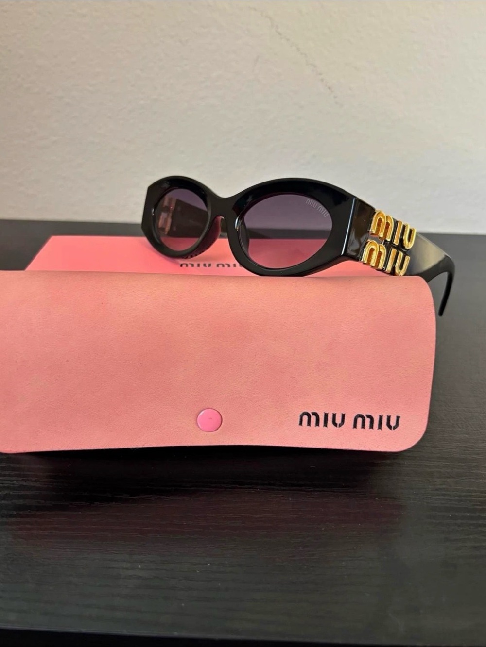 Miu Miu Black Oval Sunglasses with Gold Temple Accents